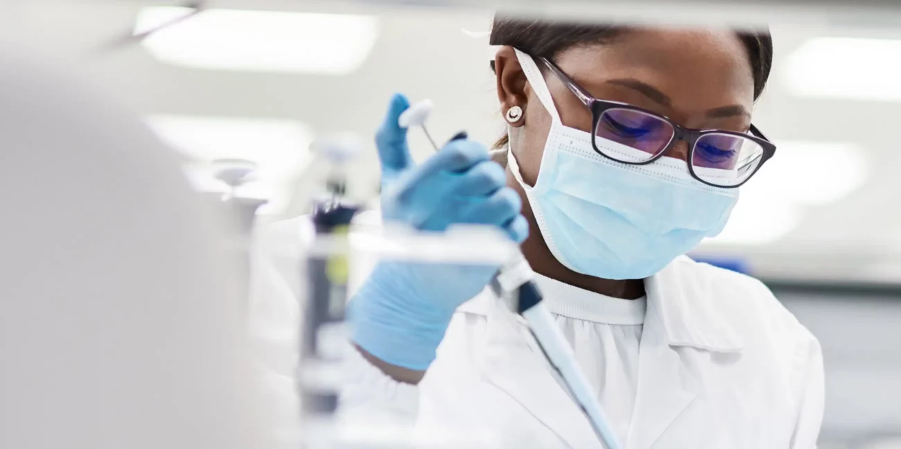 A researcher wearing a face mask in a lab carrying out a medial research task